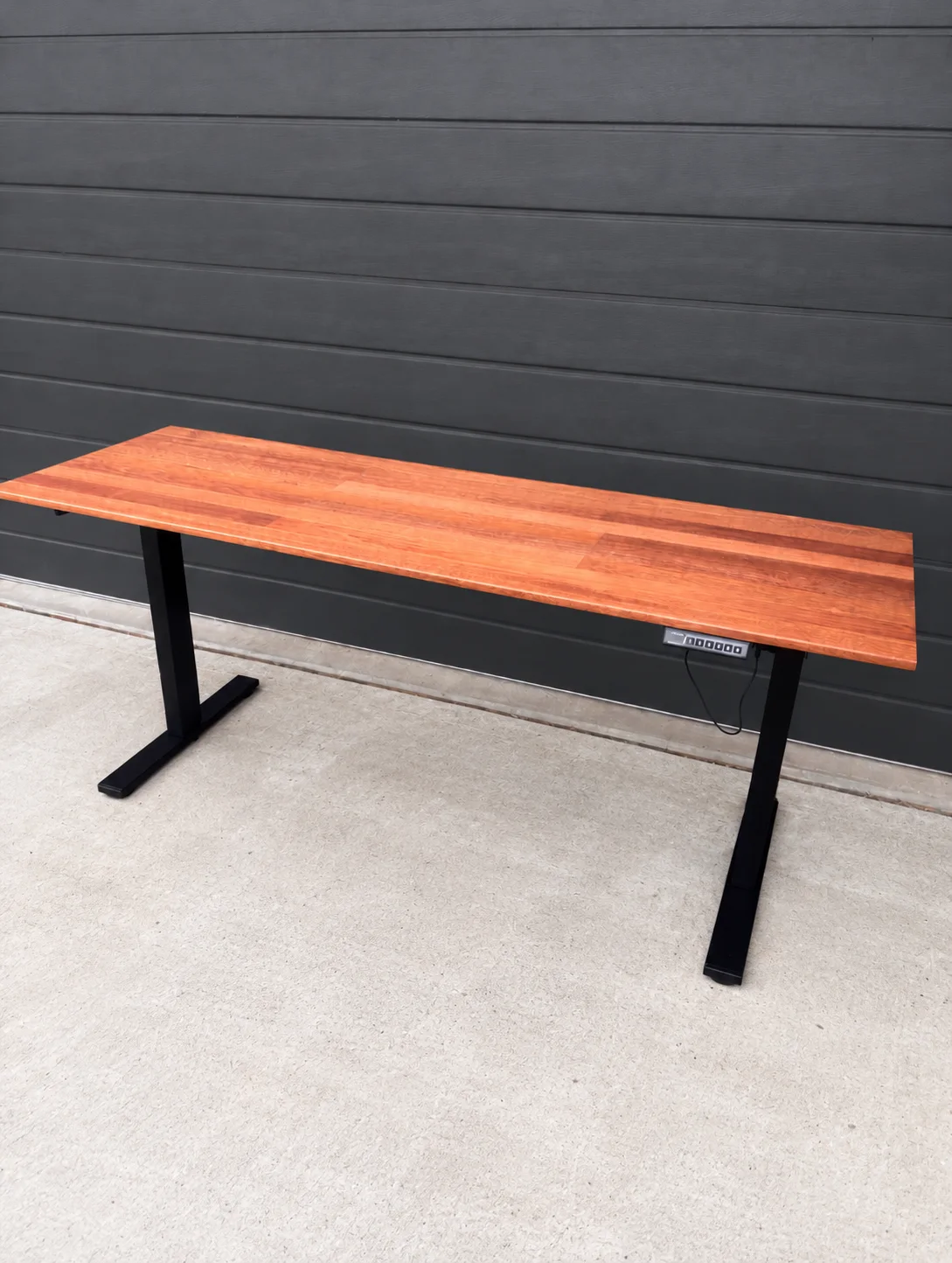 Handcrafted Merbau standing desk against a charcoal wall